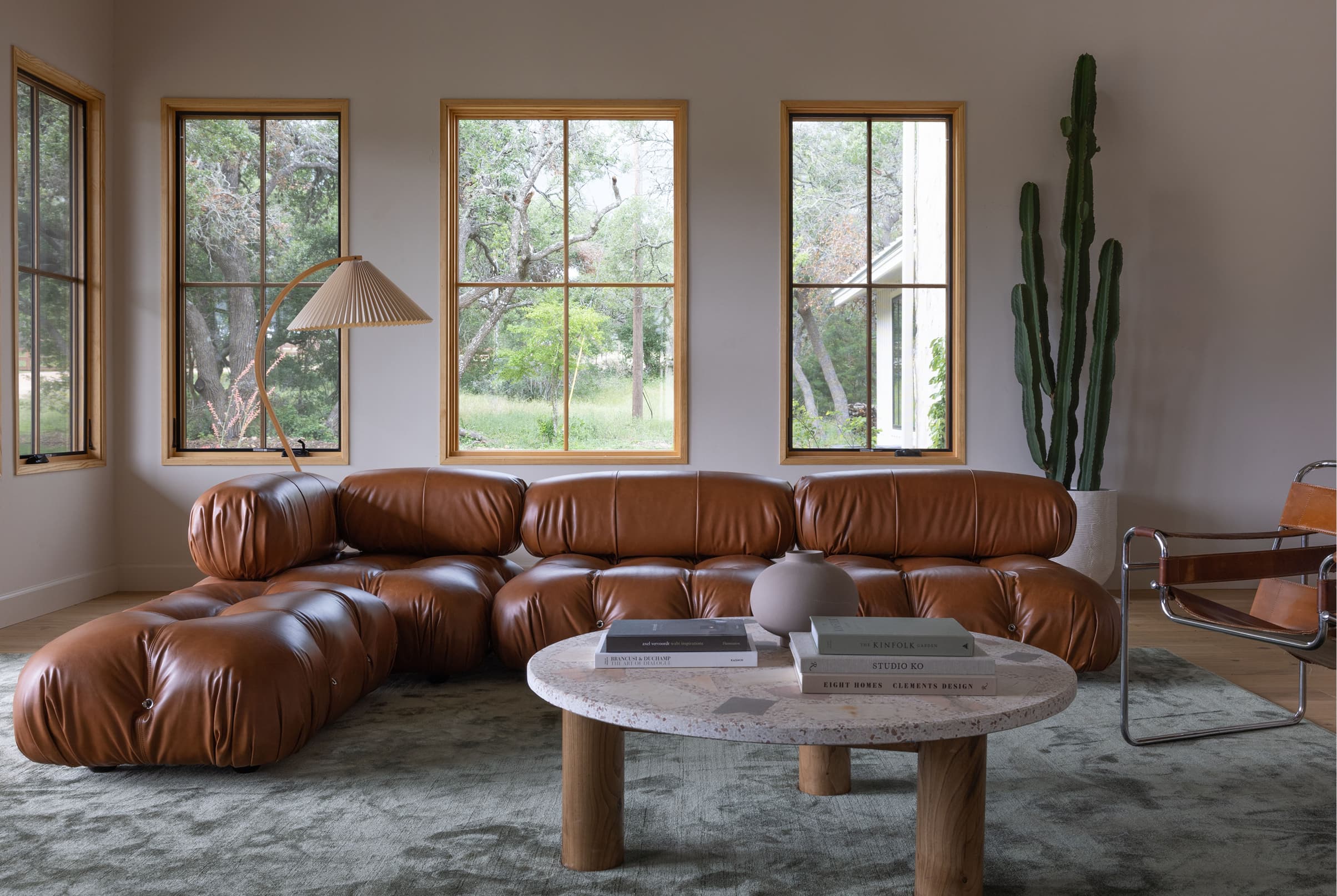 Living room interior with leather sofa and wood Marvin Elevate Casement windows with divided lites.