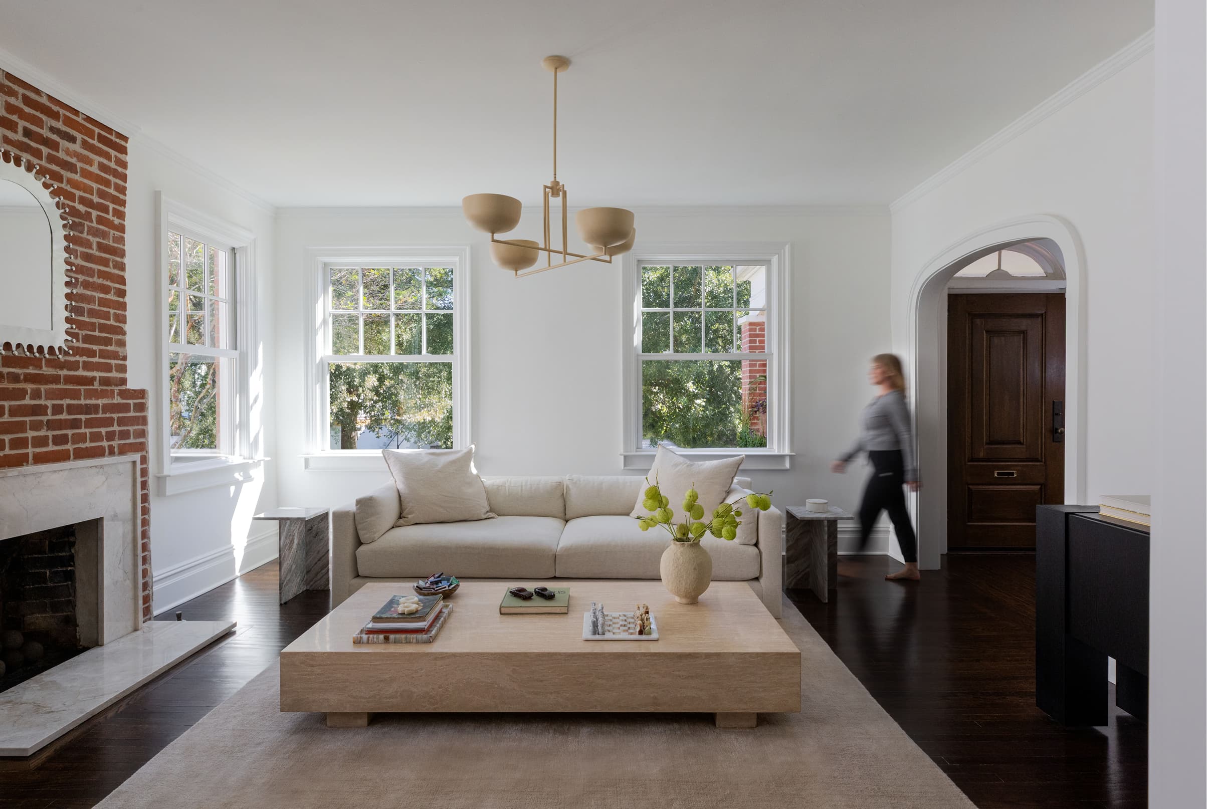 A woman walks through a white living room with white Marvin Elevate Double Hung windows with divided lites on the upper sash.